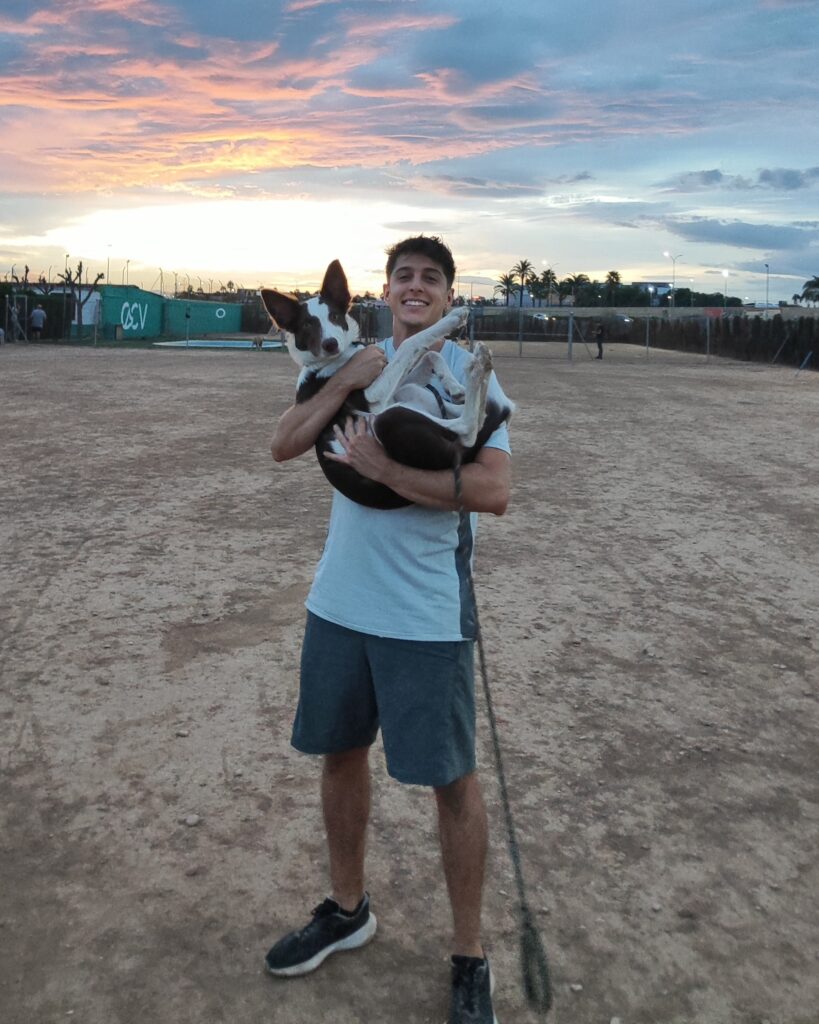 David sujetando en brazos a Loki, su border collie, durante un atardecer en Valencia