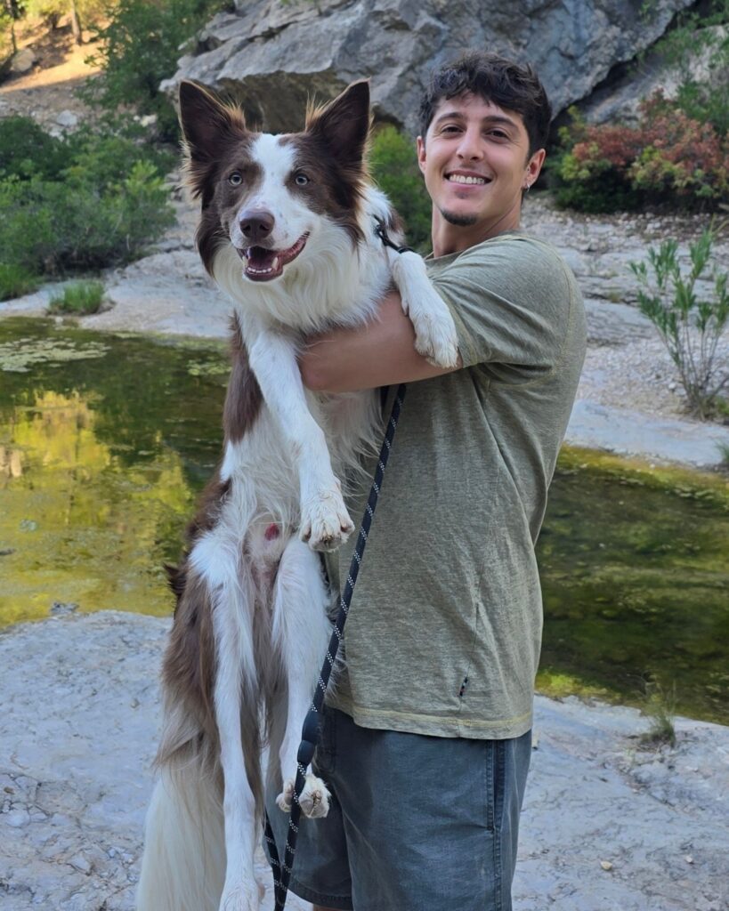 David sujetando a Loki, su border collie, junto a un río en Valencia