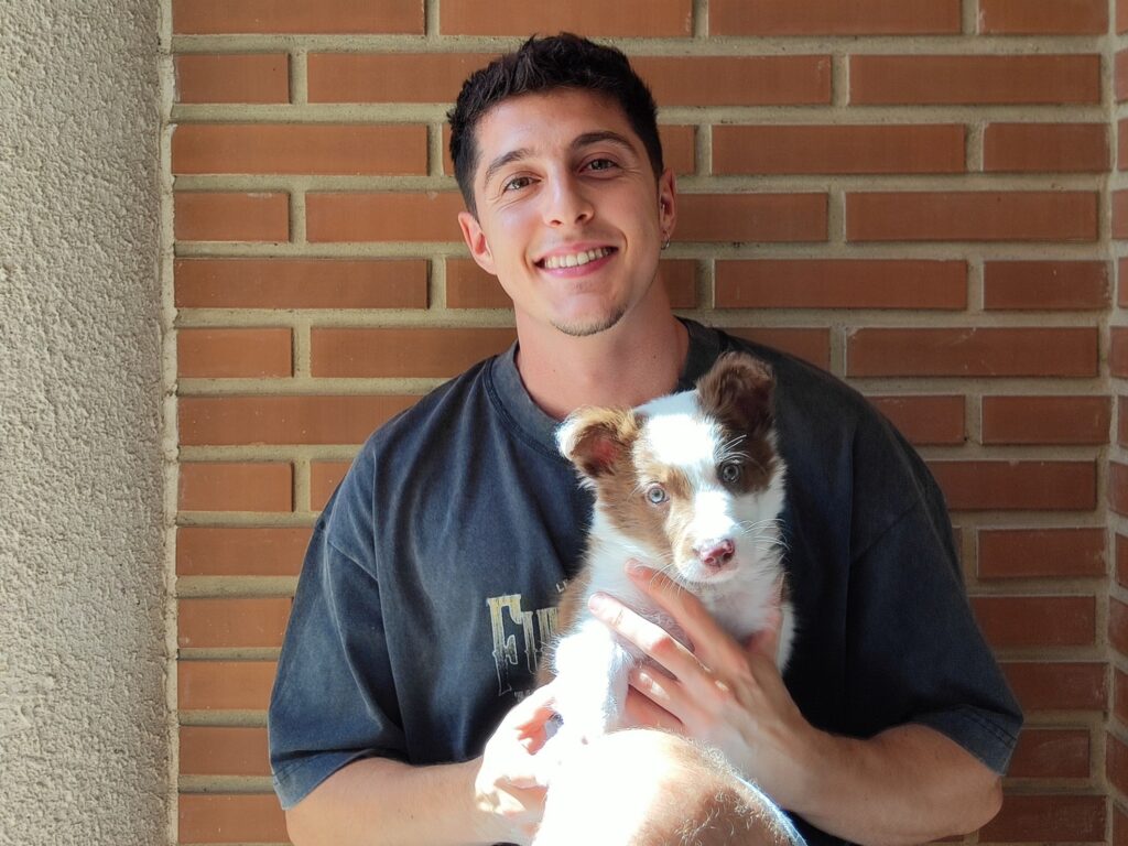 David sosteniendo en brazos a Loki, un cachorro de border collie marrón y blanco recién rescatado